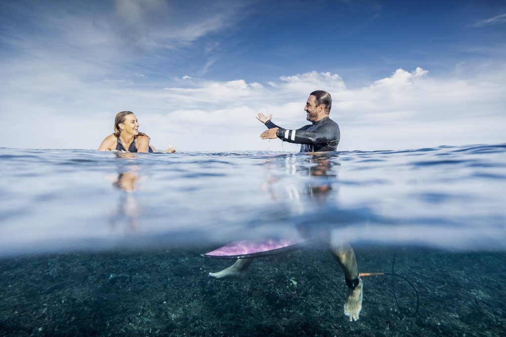 Surf coach giving feedback to a student in the water