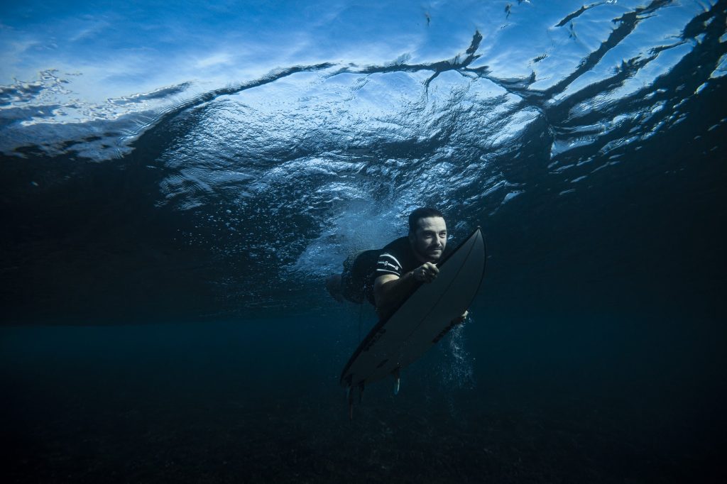 Surfer duck diving under a breaking wave